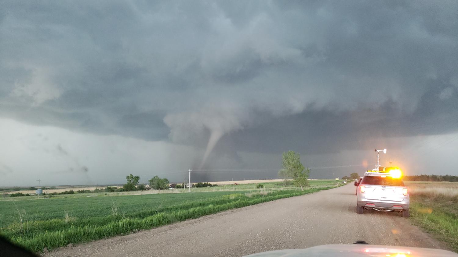 TORUS Vehicles stop at the side of the road as a tornado funnel forms to the left