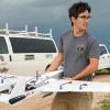 A student holding a drone in the field 