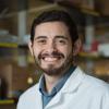 Brian Aguado standing in a lab coat.