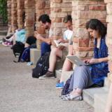 Photo of students witting with laptop and reading book