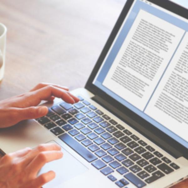 Person typing on keyboard with word document on the screen