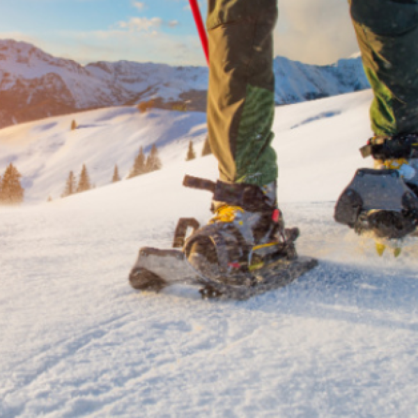 person wearing snow shoes standing on a snowy mountain