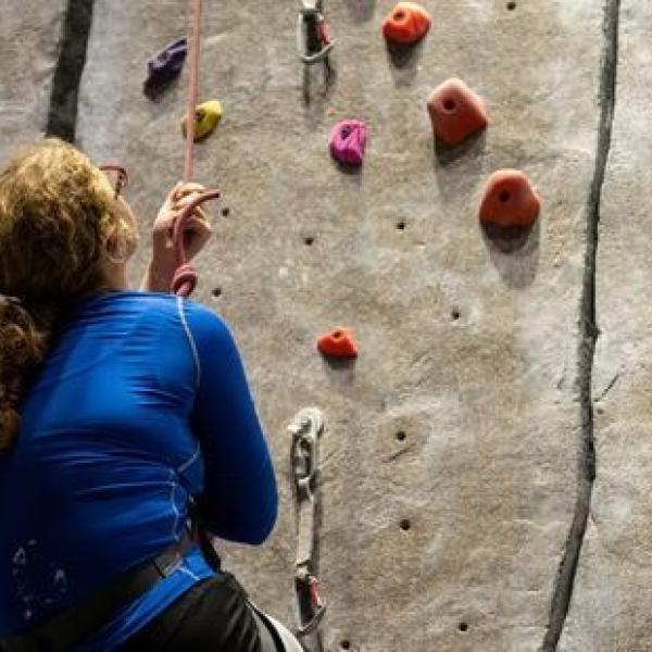 Person on belay hanging and looking at holds