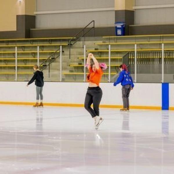 Person doing an ice skating spin at the ice rink with people skaing in the background