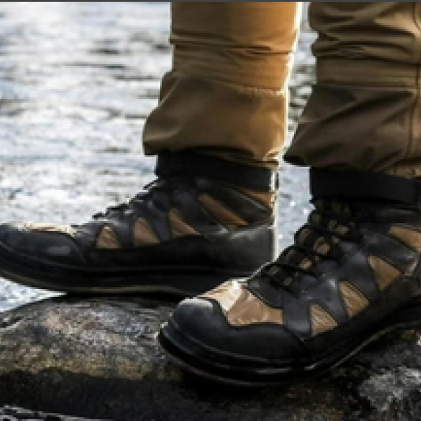Shot of person's hiking boots standing on a rock in a stream