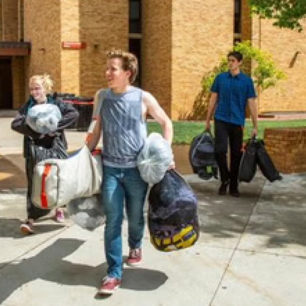 three students with bags leaving dormitory