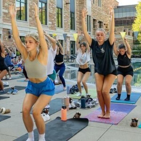 Rows of people on the pool deck doing yoga on yoga mats