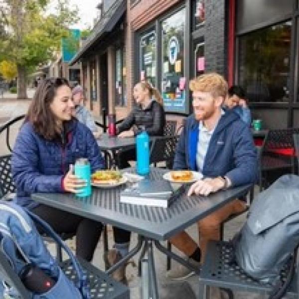 two people sitting at outdoor table at restaurant on the hill