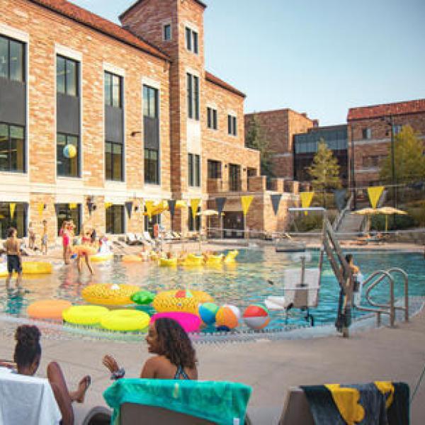 Rec Center Buff Pool with people sitting in chairs along the side, and floats and people in the pool