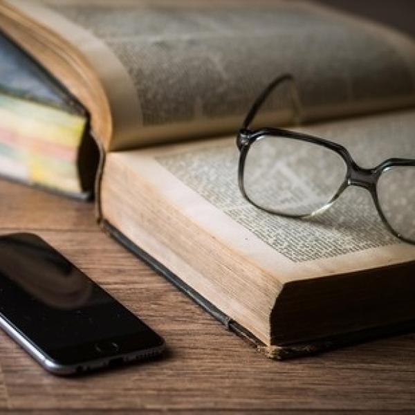 glasses resting on a book with a phone next to it on a table