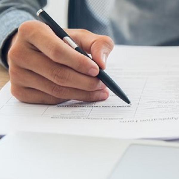Person's hand holding a pen completing an application form