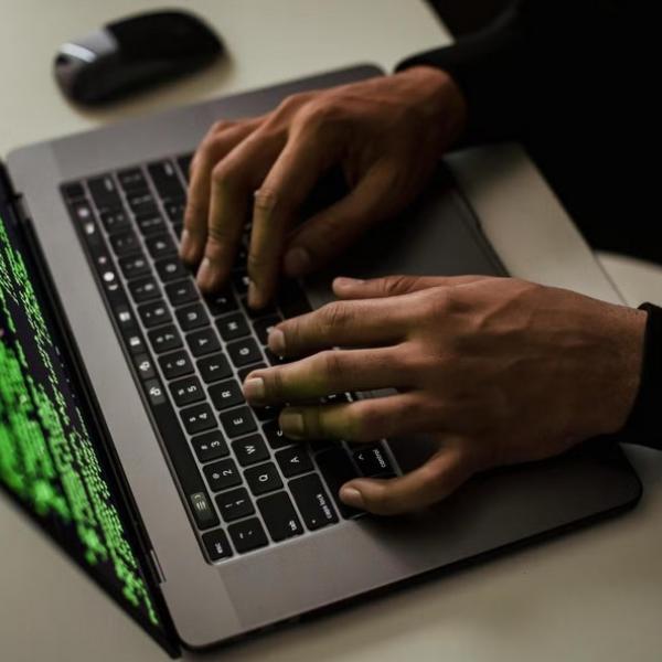 Person typing on laptop with code on screen