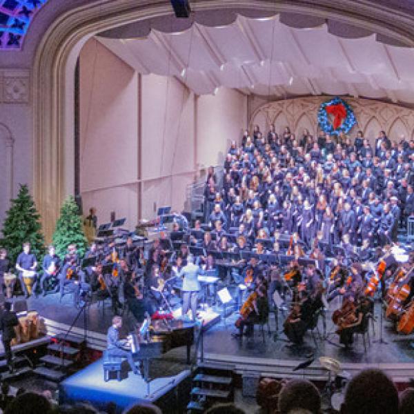 Orchestra performing in Macky Auditorium with holiday decorations