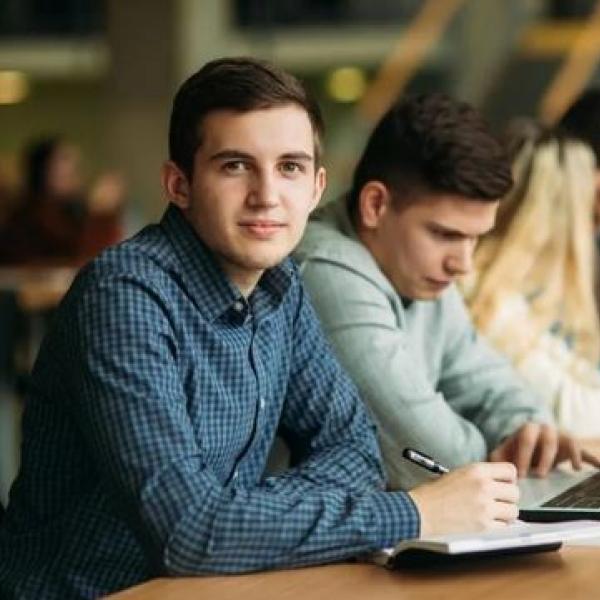 Photo of students sitting at long table in classroom