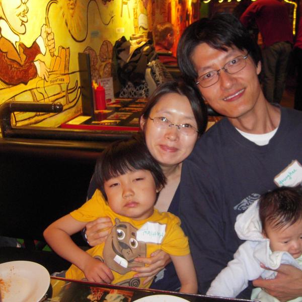 Family of four including two little kids sitting at a restaurant booth