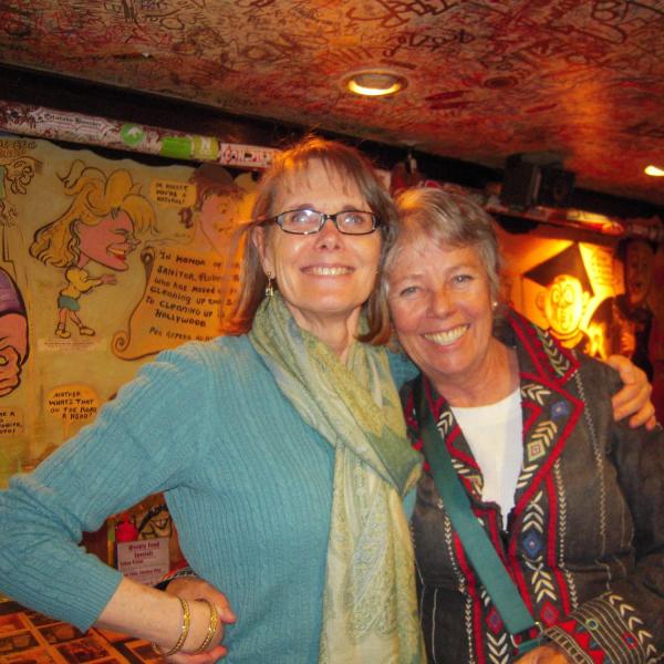 BFIS coordinator and other member in front of restaurant mural