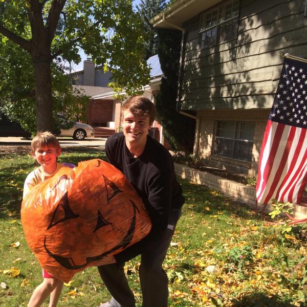 BFIS student and host brother with leaves in a jack-o-lantern bag
