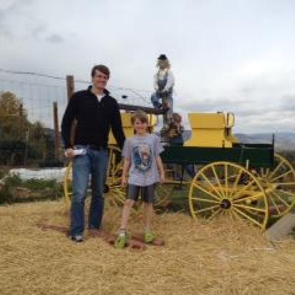 BFIS student with two younger host siblings in front of a tractor