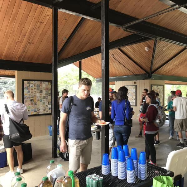 Man near stack of cups in picnic shelter