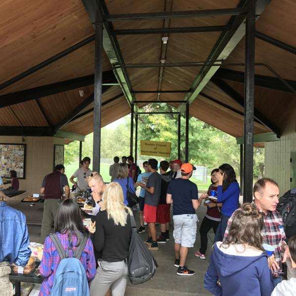 Several students and BFIS families interacting under picnic shelter