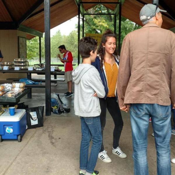 A dad and two kids smiling in a circle under the picnic shelter