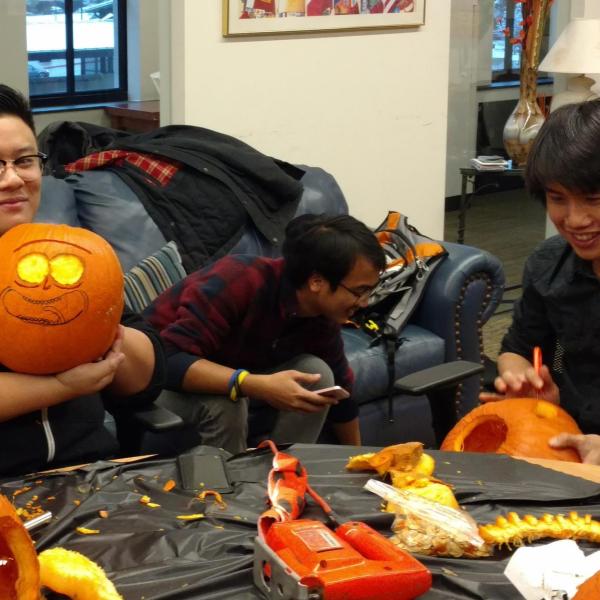 Three students carving pumpkins
