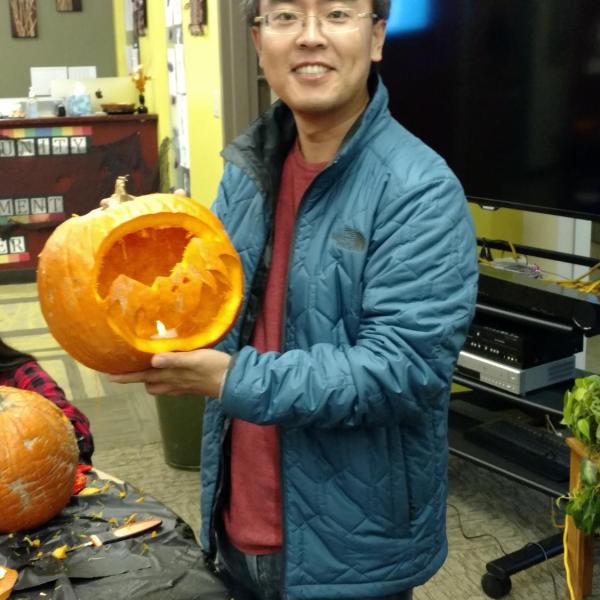 Student holding up his pumpkin with a bat design