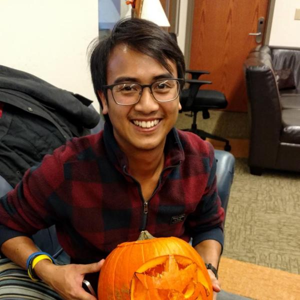 Student smiling with fully carved pumpkin