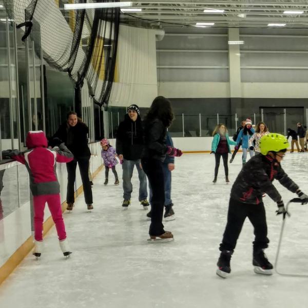 Kid ice skating with special prop and other skaters in background