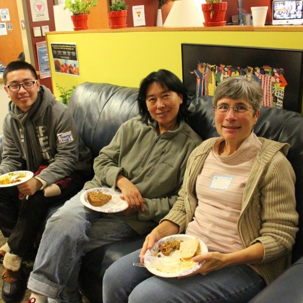Three BFIS members smiling from couch with food in hands