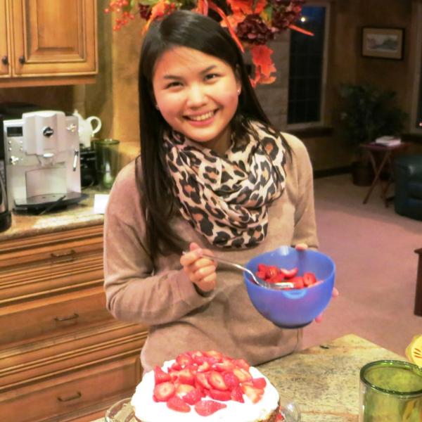 BFIS student spooning strawberries onto homemade cake