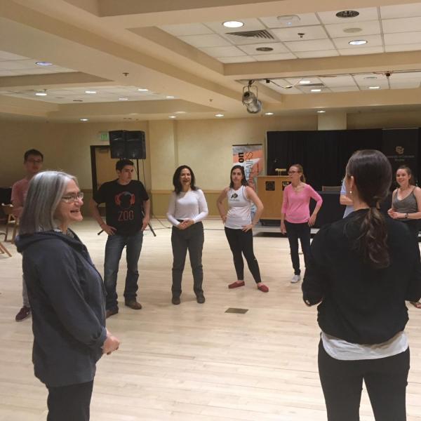 People in a circle listening to Salsa dance instructions