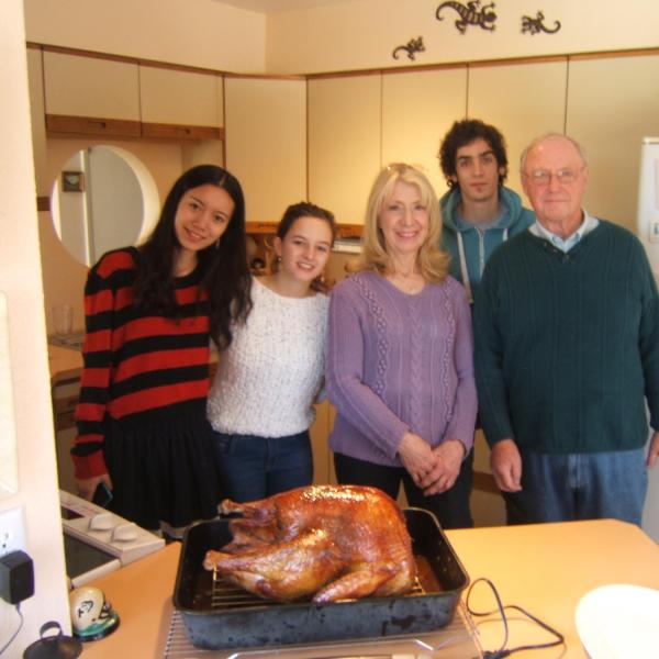 Three BFIS students and BFIS family posing in front of a turkey