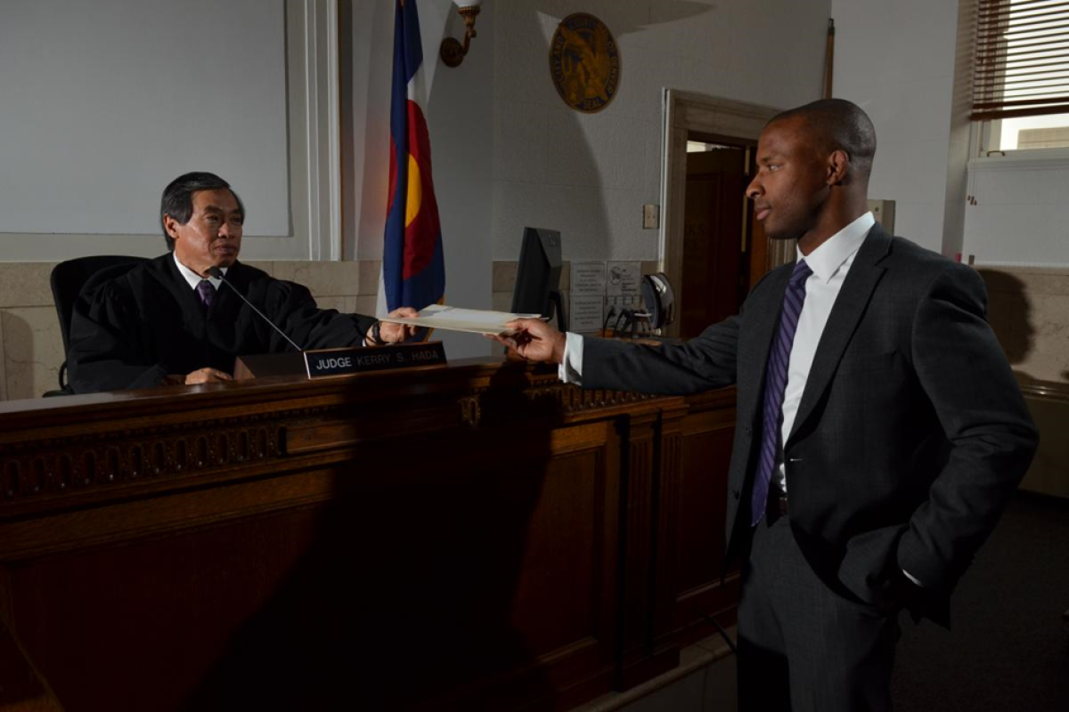 Lawyer handing judge paperwork in a Colorado court room