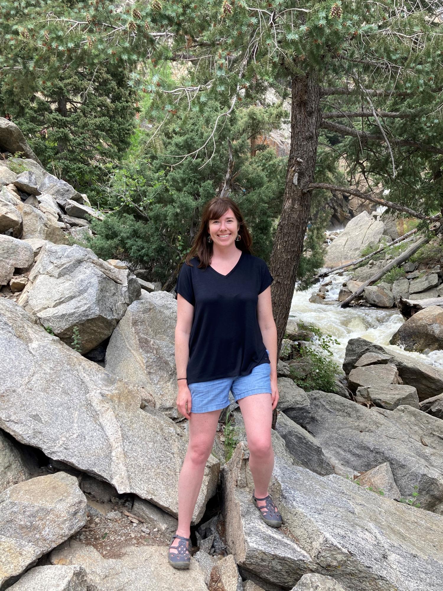 Erica Coffelt standing on rocks with stream in background