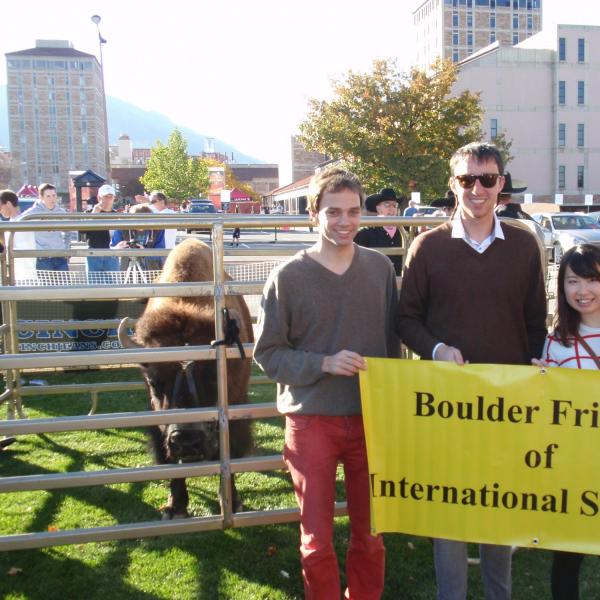 Four BFIS members holding BFIS banner in front of Ralphie, the buffalo