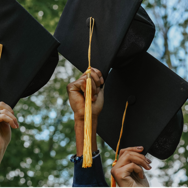 three hands holding graduation caps