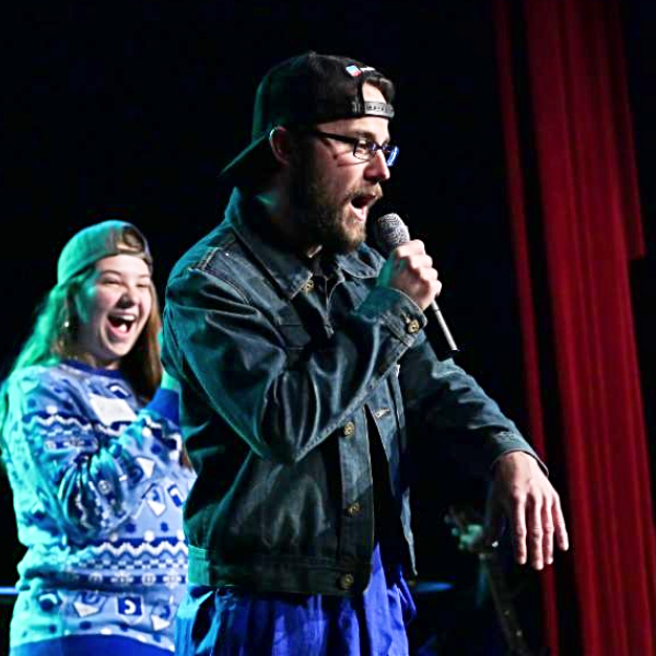 Students performing on stage, mics in hand, during the 2017 Hebrew Schmooze-A-Palooza