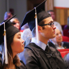 Students sitting in theater seating at graduation, dressed in cap & gown