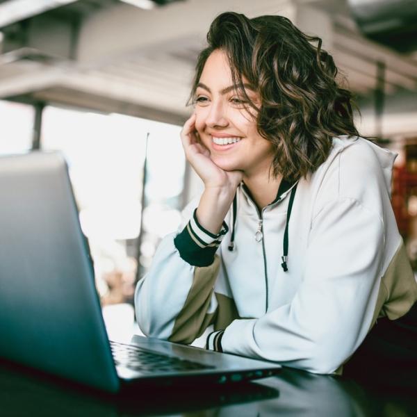 A woman in a white shirt looking at laptop screen.