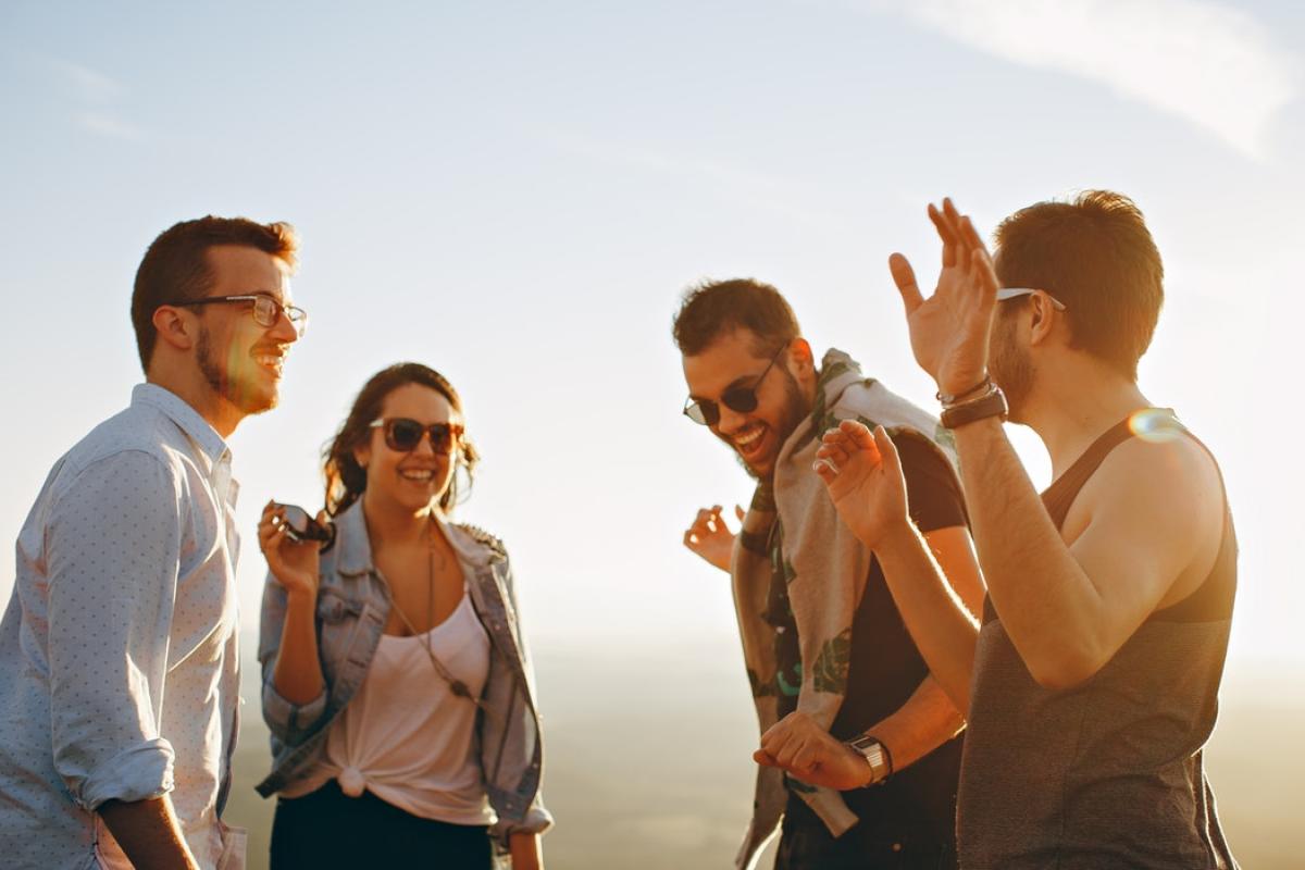 A group of 3 men and 1 women talking and laughing.