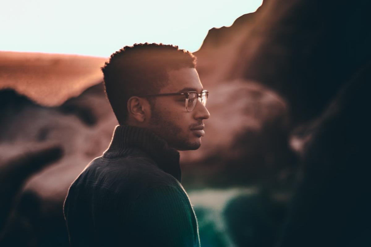 Profile of a man standing in front of a rock formation.