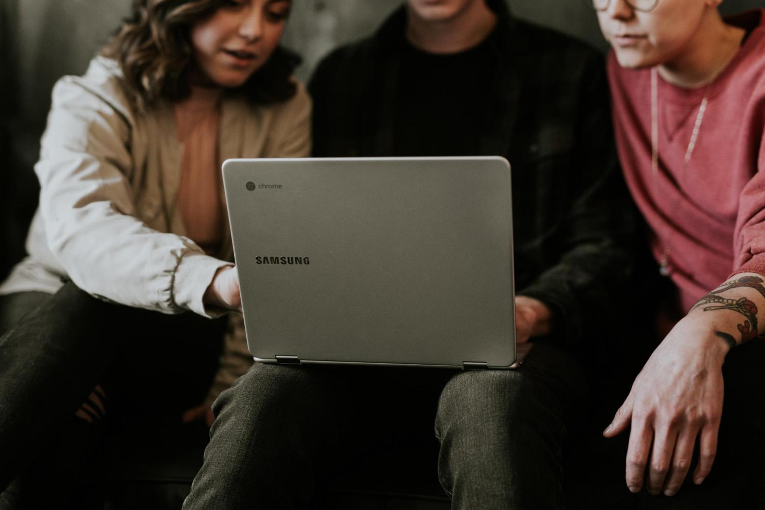 People sitting around laptop point at screen.