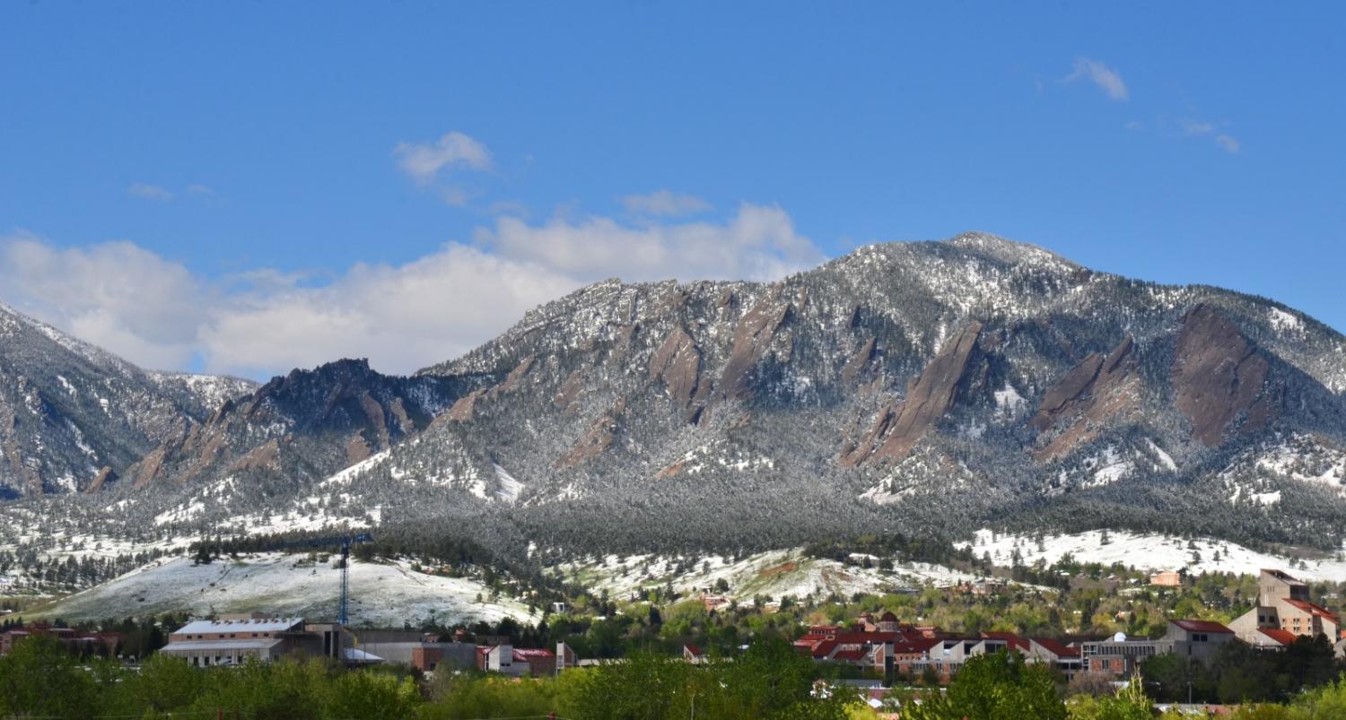 Spring in Boulder with snow in the foothills and grass growing around campus