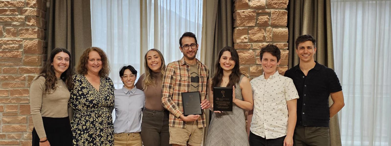 Group of seven young adults standing with Prof. Pezzullo, holding an award