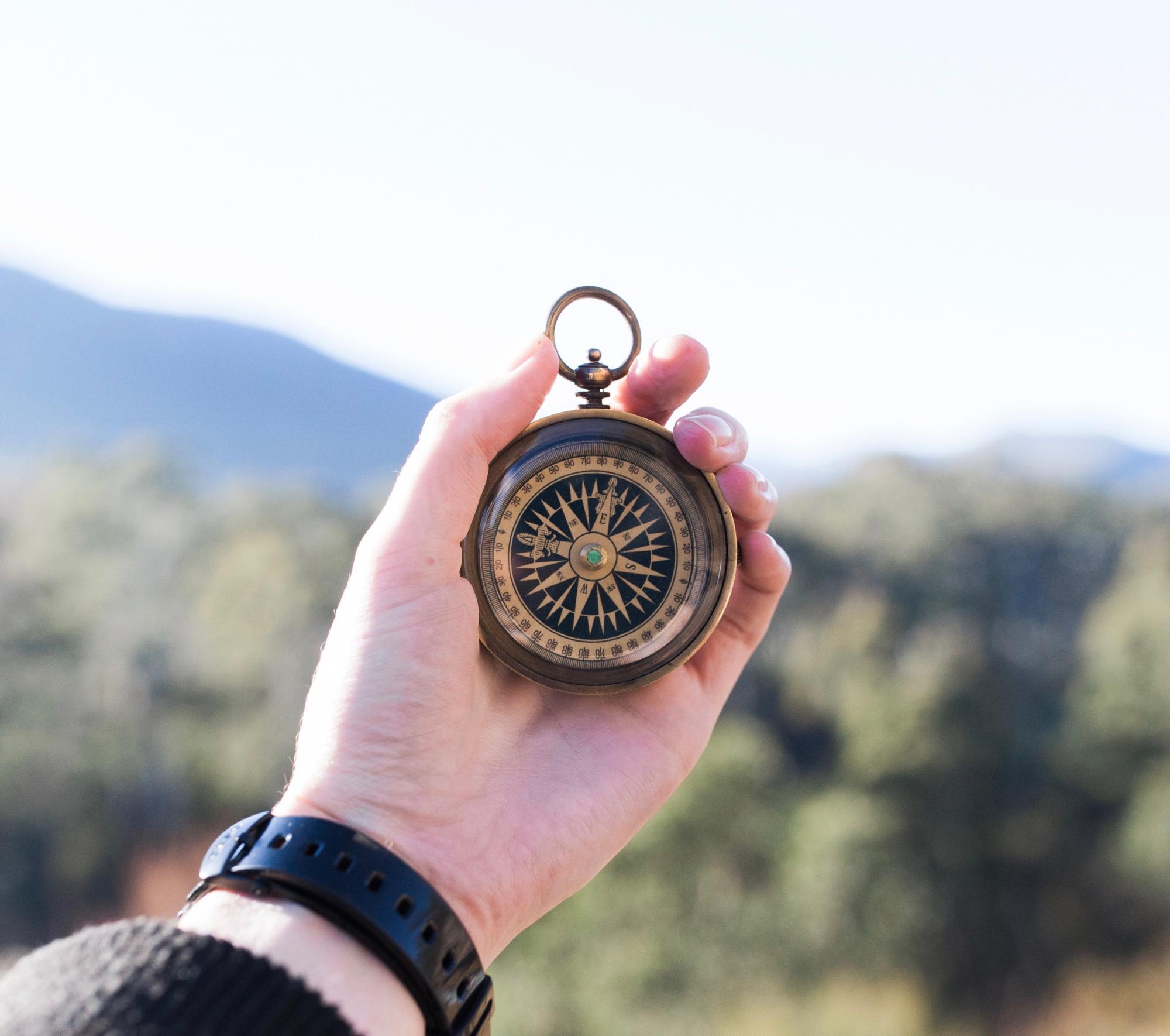 A hand holding up a compass