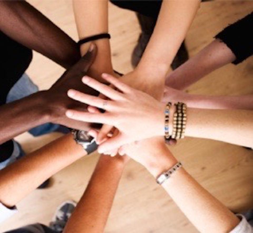 A circle of people with hands on top of each other