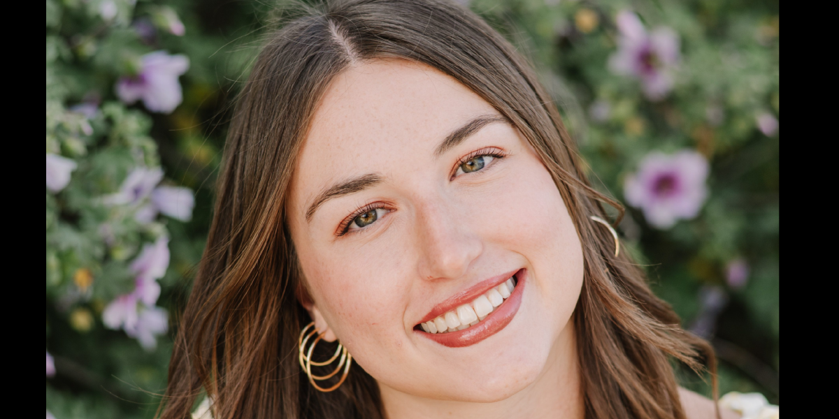 Liv with brunette hair and yellow top smiling at the camera