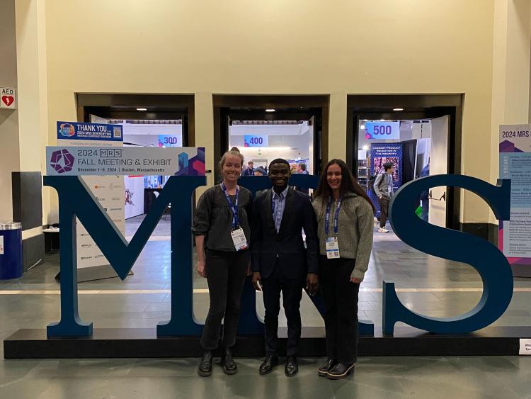 Olivia, Samson, Alyssa standing in front of big letters that say MRS.