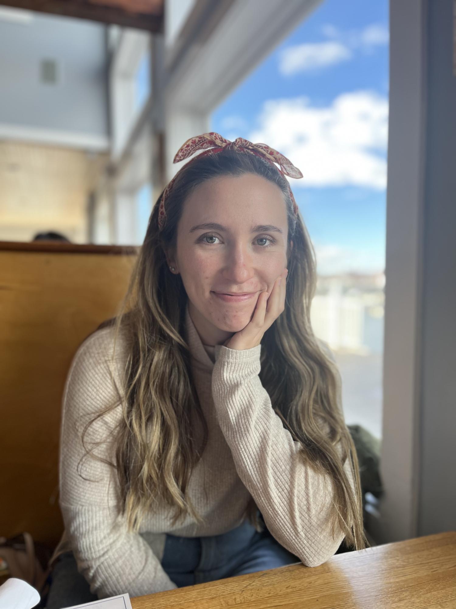 A woman seated in a booth smiling at the camera.